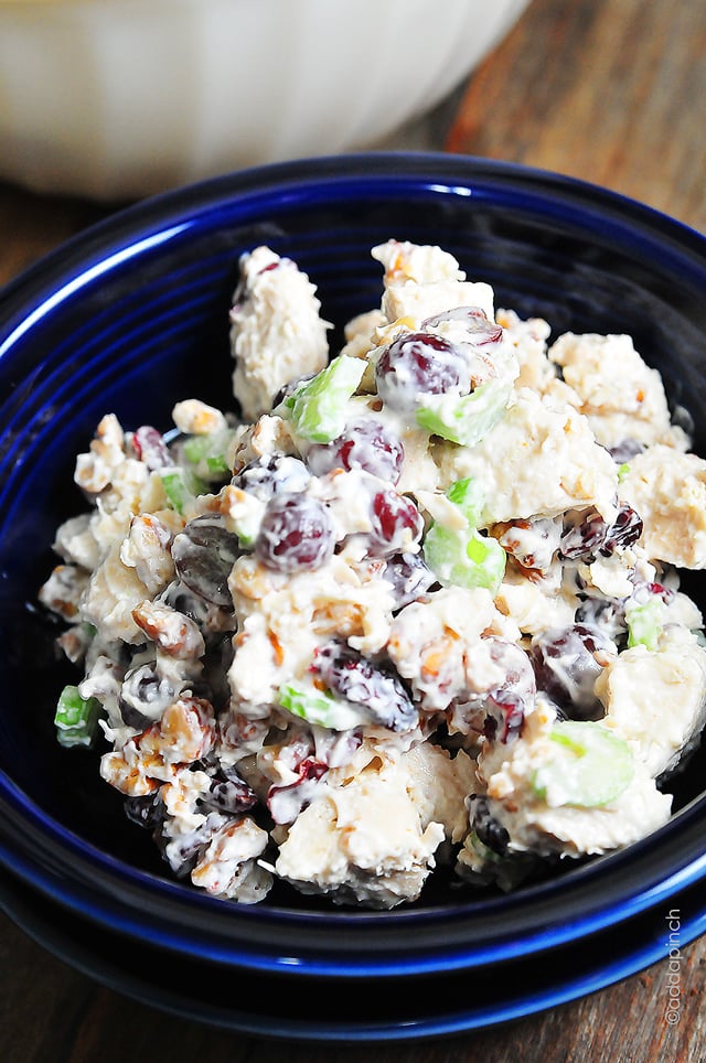 Closeup photograph of chicken salad made with grapes, raisins, celery and pecans in a blue bowl.