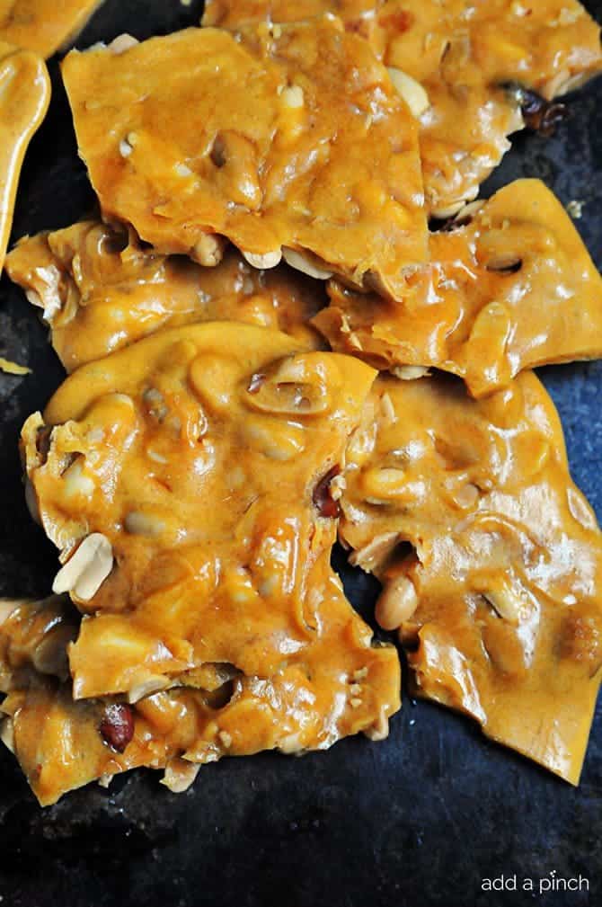 Large broken pieces of peanut filled peanut brittle candy on a dark background // addapinch.com